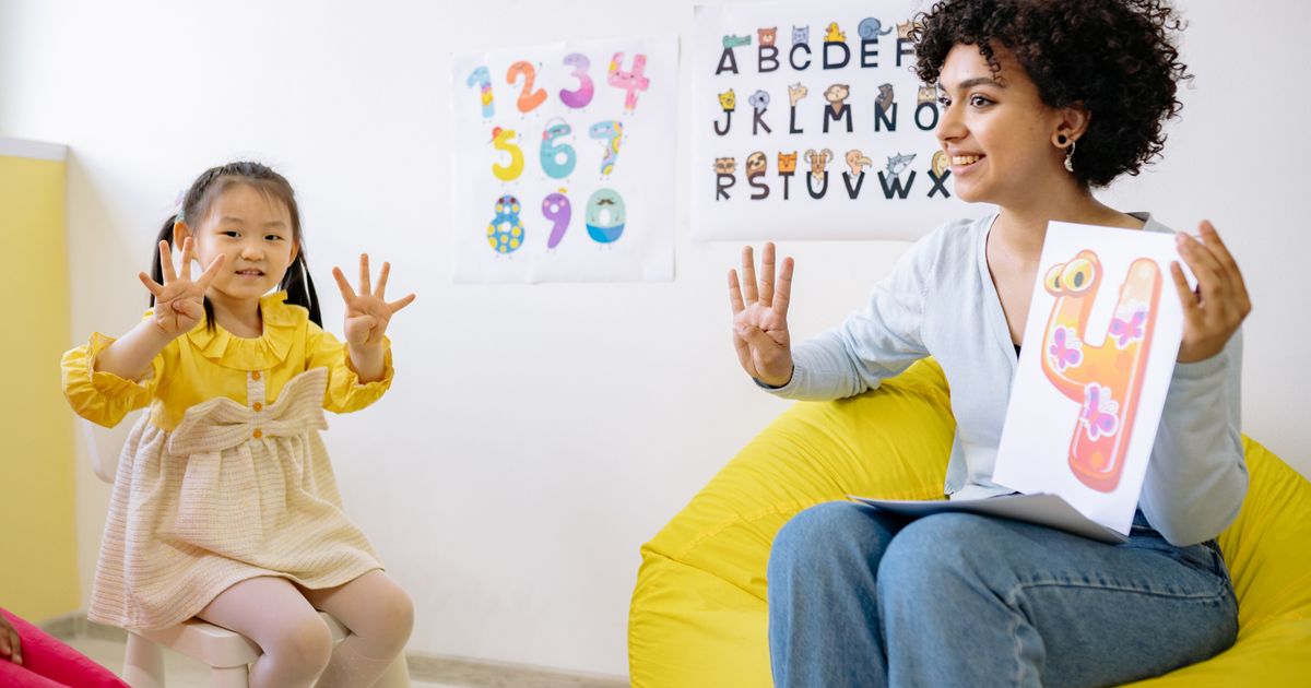 Caregiver and child sitting together with school materials