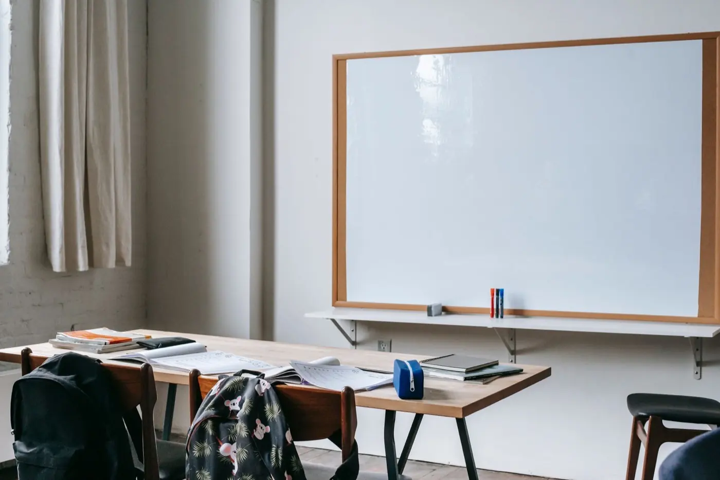 Quiet classroom desk with notebooks and an empty whiteboard