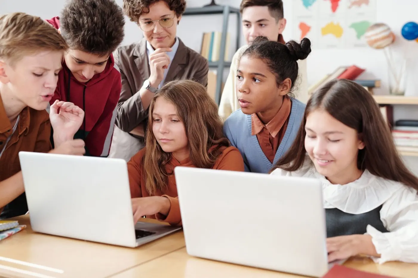 Teacher and students reviewing work together on laptops